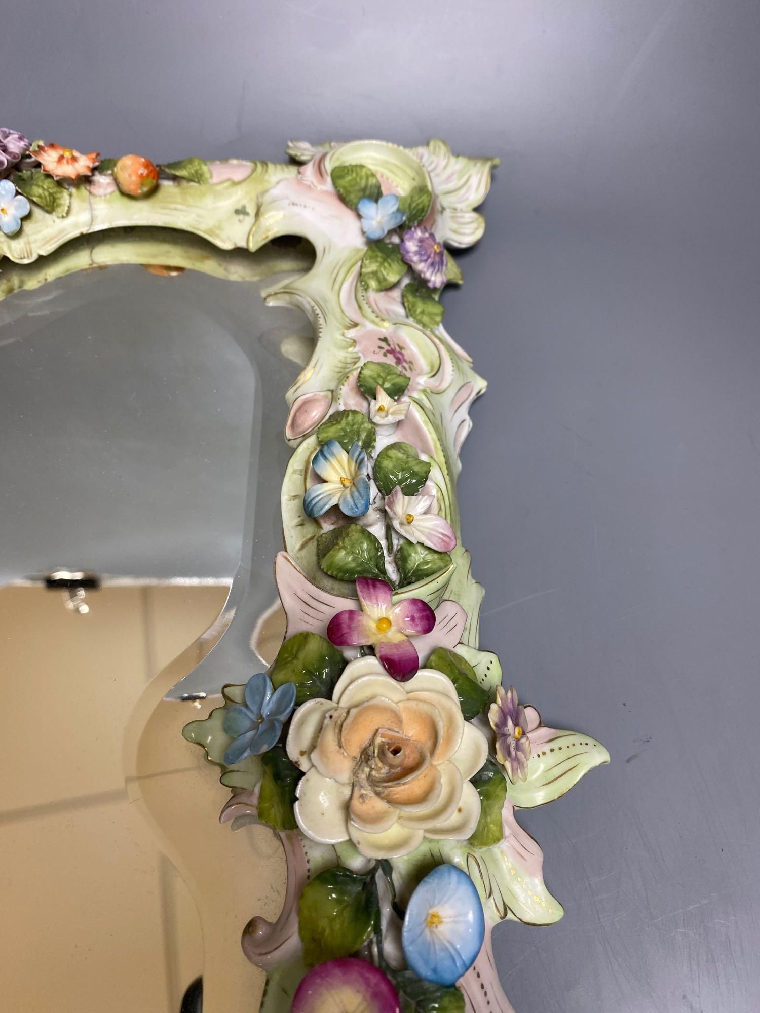 A porcelain floral encrusted wall mirror, German, Von Schierholz, 30 x 40cm